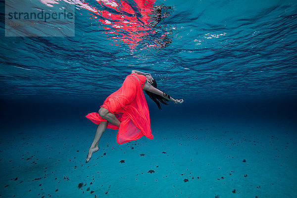 Frau unter Wasser in rotem Kleid