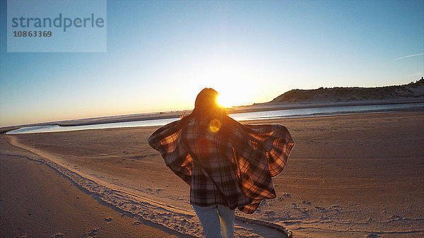 Rückansicht einer Frau mit wehendem Schal  die den Sonnenuntergang von Cannon Beach  Oregon  USA  aus beobachtet