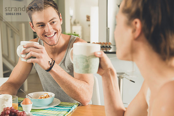 Junges Paar trinkt Frühstückskaffee am Küchentisch
