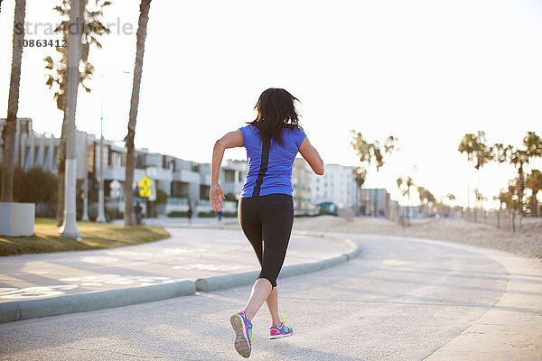 Rückansicht einer Frau in Sportkleidung in voller Länge  die auf der Straße joggt