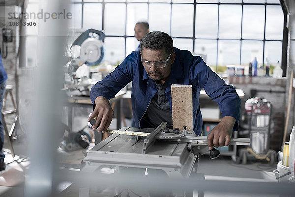 Schreiner mit Maschine zum Messen von Holz in der Werkstatt