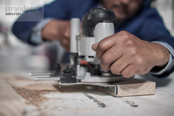 Nahaufnahme einer Zimmermannshand mit einem Stichsägewerkzeug in der Werkstatt