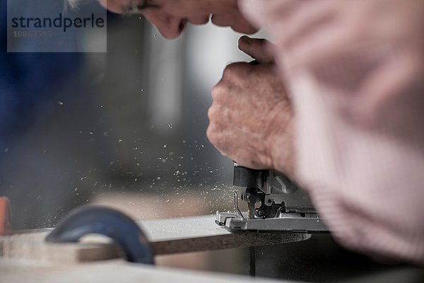 Schnappschuss eines leitenden Zimmermanns mit einem Stichsägewerkzeug in der Werkstatt