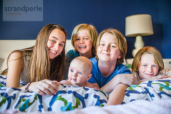 Brüder und Schwester liegen vorne auf dem Bett