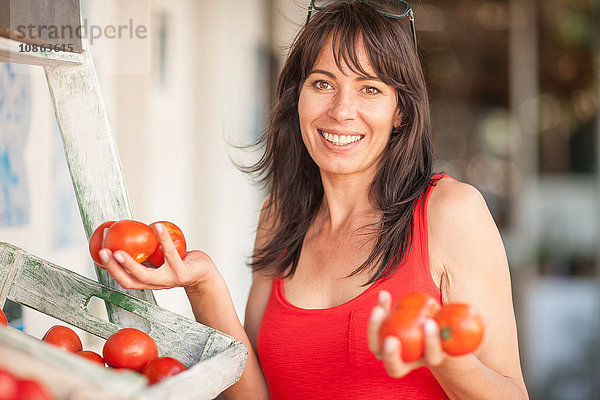 Frau mit Händen voller Tomaten auf dem Markt