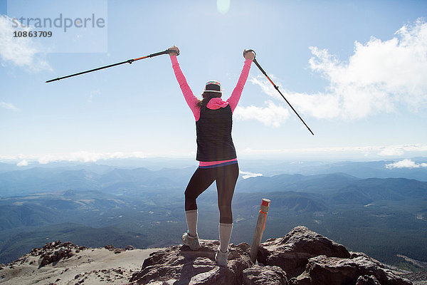 Junge Frau auf dem Berggipfel  die Wanderstöcke in der Luft hält  Rückansicht  Mt. St. Helens  Oregon  USA