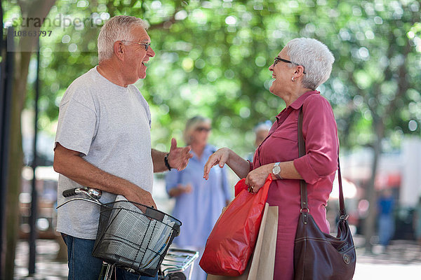 Älterer Mann und reife Frau unterhalten sich in der Stadt