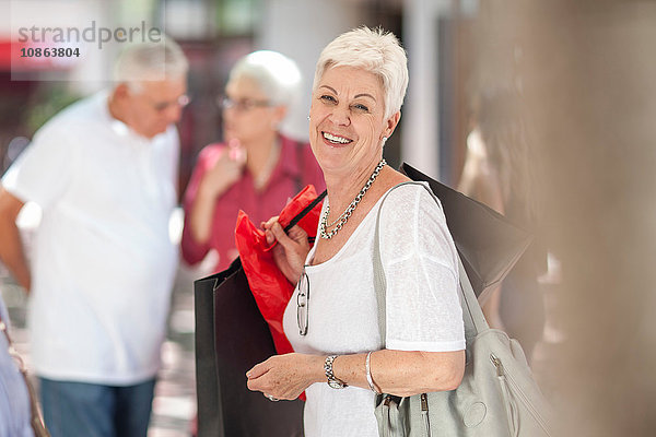 Porträt einer älteren Frau mit Einkaufstaschen in der Stadt