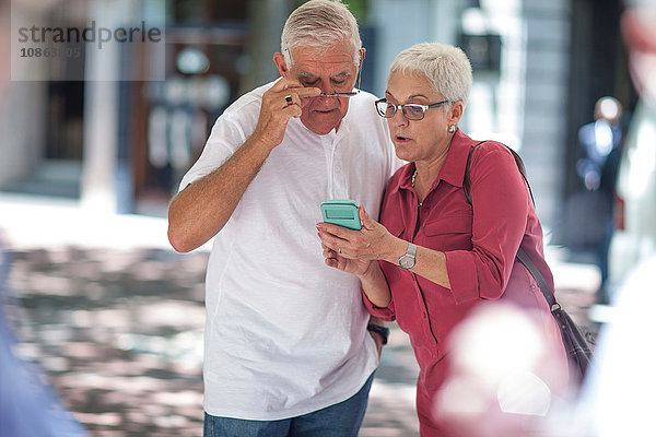 Älterer Mann und Frau lesen Smartphone in der Stadt