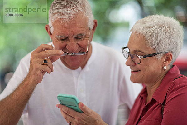 Älterer Mann und Frau mit Brillenträger lesen Smartphone in der Stadt