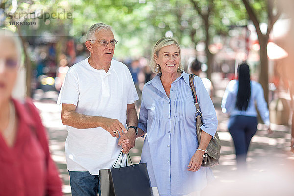 Älterer Mann und Frau halten beim Einkaufen in der Stadt Händchen