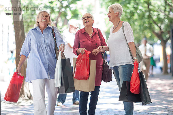 Ältere und reifere Frauen schlendern mit Einkaufstaschen in der Stadt