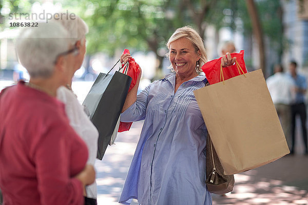 Ältere und reifere Frauen halten Einkaufstüten in der Stadt hoch