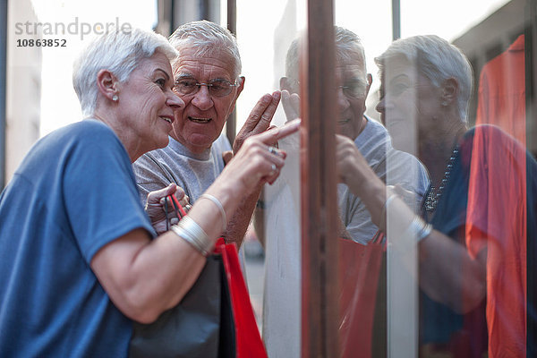 Älteres Ehepaar zeigt auf Stadtschaufenster