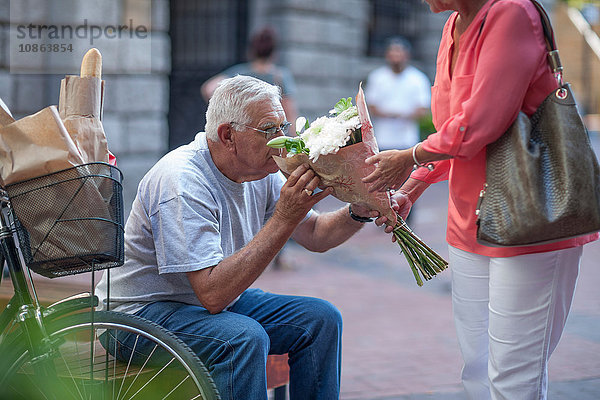 Älterer Mann riecht Bouquet auf Stadttreppe