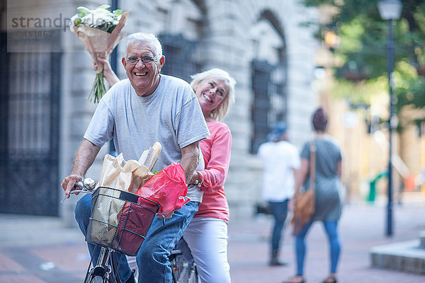 Älterer Mann und Frau halten in der Stadt gemeinsam einen Blumenstrauss hoch