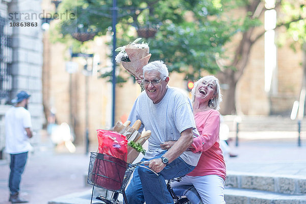 Älterer Mann und Frau halten in der Stadt Blumensträuße hoch