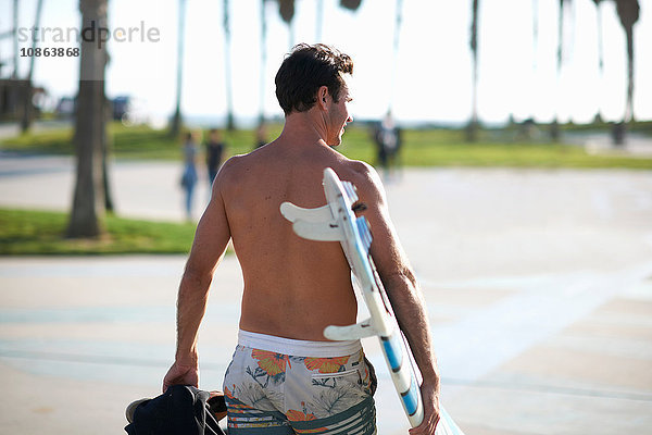 Rückansicht eines Mannes mit Surfbrett am Venice Beach  Kalifornien  USA