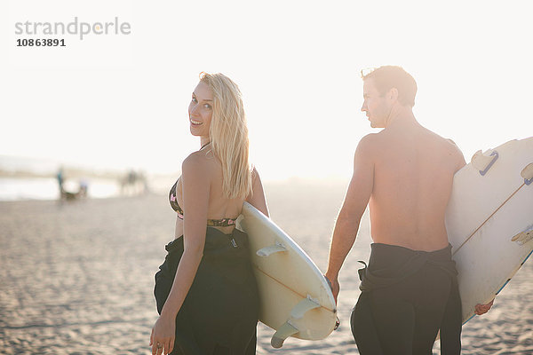 Surferpaar mit Surfbrettern am sonnenbeschienenen Strand von Venice Beach  Kalifornien  USA