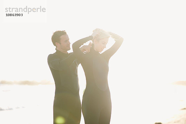 Surfer-Paar mit Neoprenanzügen am sonnenbeschienenen Venice Beach  Kalifornien  USA