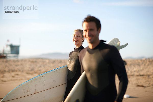 Surferpaar beim Spaziergang mit Surfbrettern am Venice Beach  Kalifornien  USA