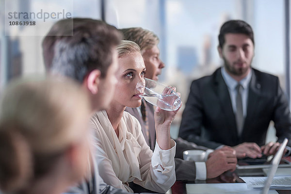 Geschäftsfrau trinkt Wasser am Konferenztisch