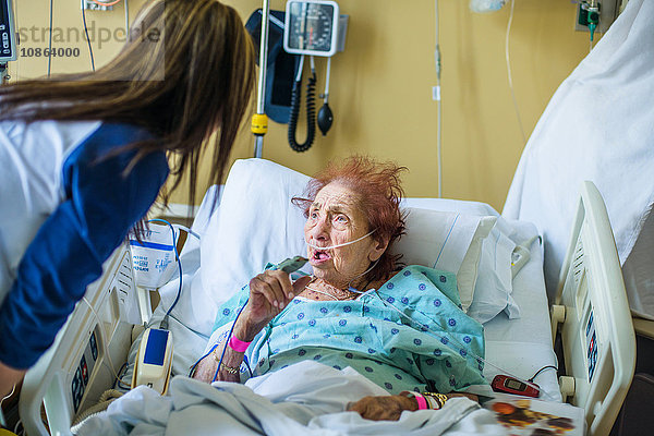 Patient im Krankenhausbett im Gespräch mit Besucher