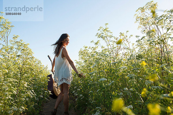 Frau mit Gitarre im Feld der Wildblumen