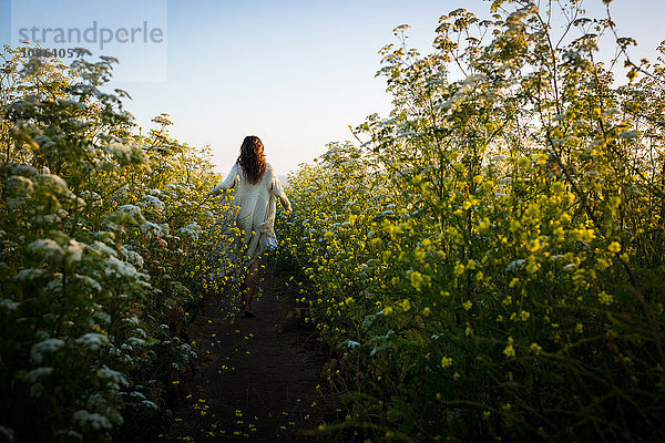 Frau geht durch ein Feld mit Wildblumen