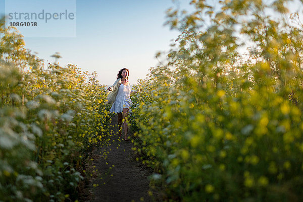 Frau geht durch ein Feld mit Wildblumen