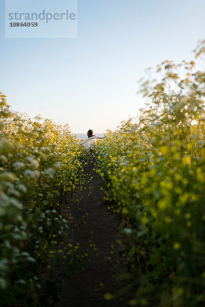 Frau geht durch ein Feld mit Wildblumen