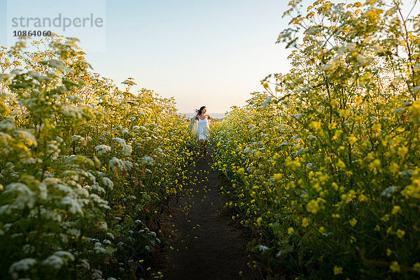 Frau geht durch ein Feld mit Wildblumen