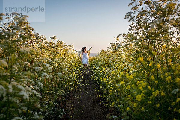 Frau geht durch ein Feld mit Wildblumen