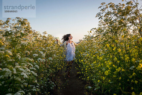 Frau geht durch ein Feld mit Wildblumen