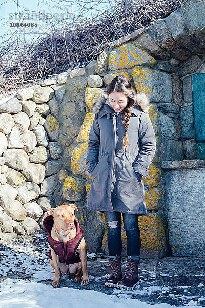 Gesamtansicht einer Frau mit Hund vor einem Trockensteingebäude