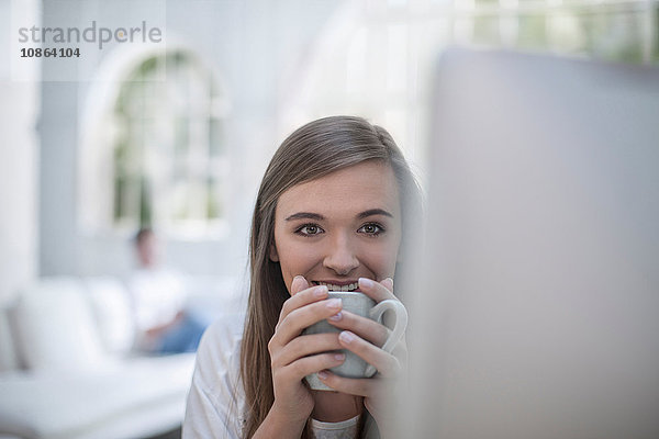 Frau trinkt Kaffee vor dem Computer