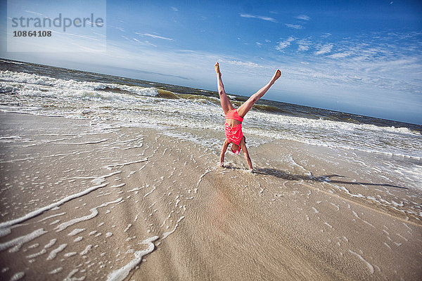 Mädchen macht Handstand am Strand
