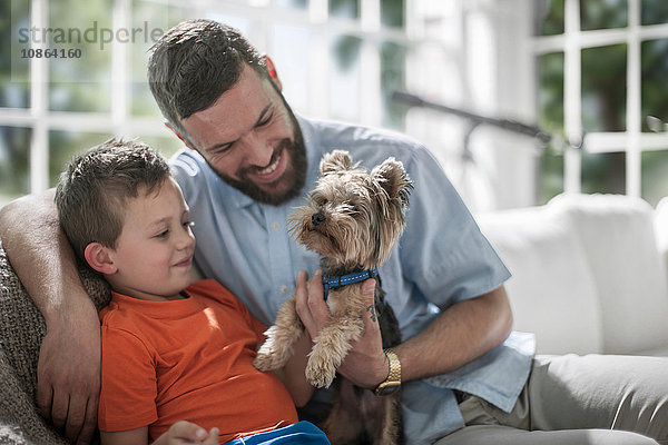 Vater und Sohn mit Haushund auf dem Sofa