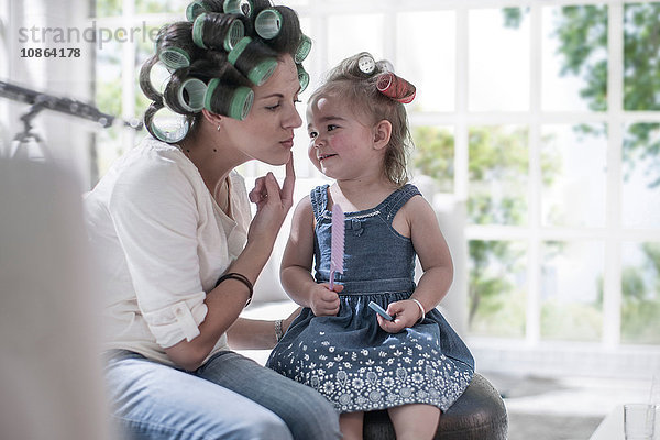 Mutter in Haarrollen zeigt Wange zur Tochter