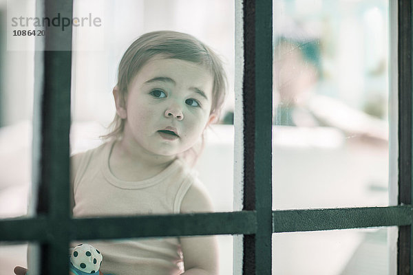 Kleines Mädchen schaut durchs Fenster