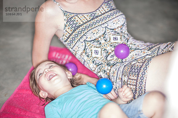 Mutter und Tochter spielen mit Bällen auf dem Boden