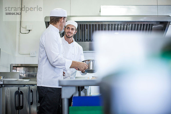 Köche unterhalten sich und bereiten das Essen in der Küche vor