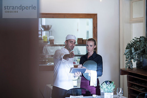 Kellnerin und Koch diskutieren im Restaurant