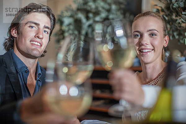 Paar stoßt mit einem Freund im Restaurant an