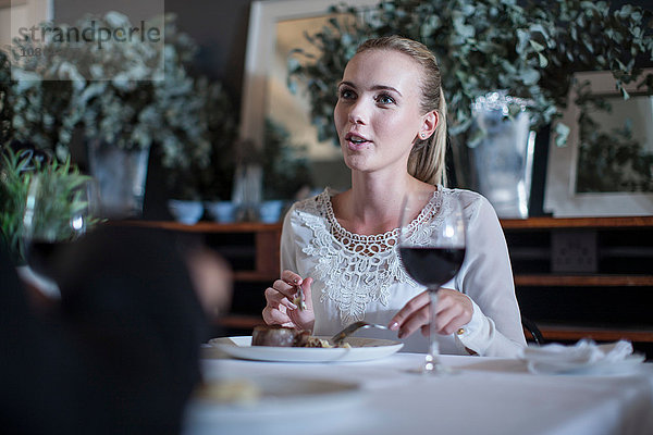 Frau speist und plaudert mit Freundin im Restaurant