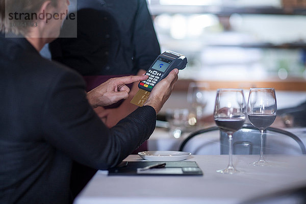 Kunde zahlt mit Kreditkarte an Kellnerin im Restaurant