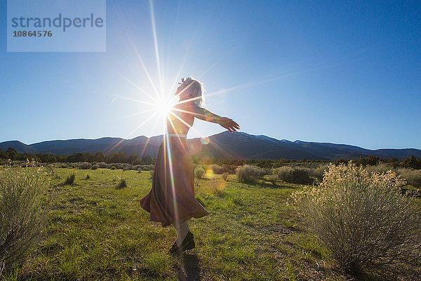 Junge Frau tanzt mit offenen Armen im sonnenbeschienenen Tal  Ely  Nevada  USA