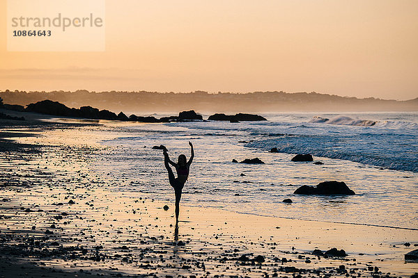 Silhouette einer Balletttänzerin  die bei Sonnenuntergang am Strand auf einem Bein steht  Los Angeles  Kalifornien  USA