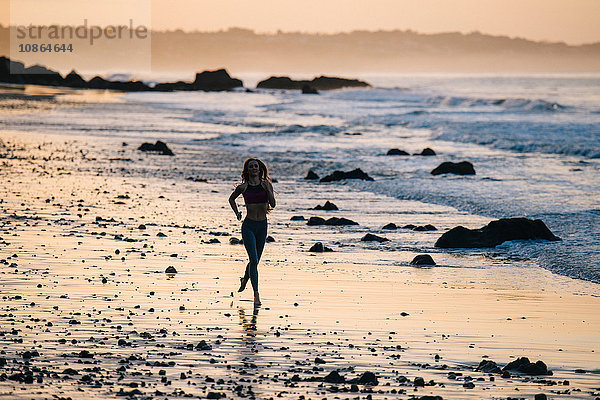 Silhouettierte Läuferin läuft bei Sonnenuntergang am Strand  Los Angeles  Kalifornien  USA