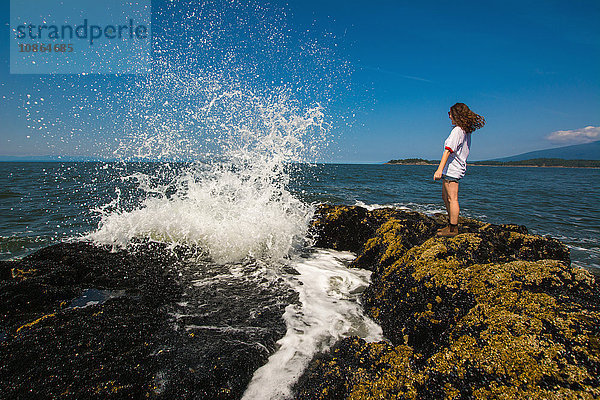 Junge Frau steht auf Felsen am Ozean  Bowen Island  Britisch-Kolumbien  Kanada